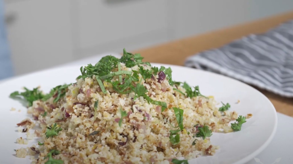 A vibrant pile of cauliflower rice, seasoned and topped with fresh herbs