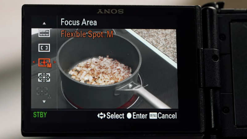 A Close-Up of A Camera Screen Displaying a Focus Area Setting While Filming Onions Cooking in A Pan