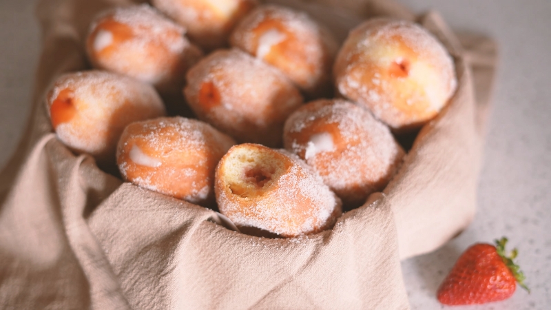 A Basket of Sugar-Coated Malasadas Filled with Cream and Strawberry Jam