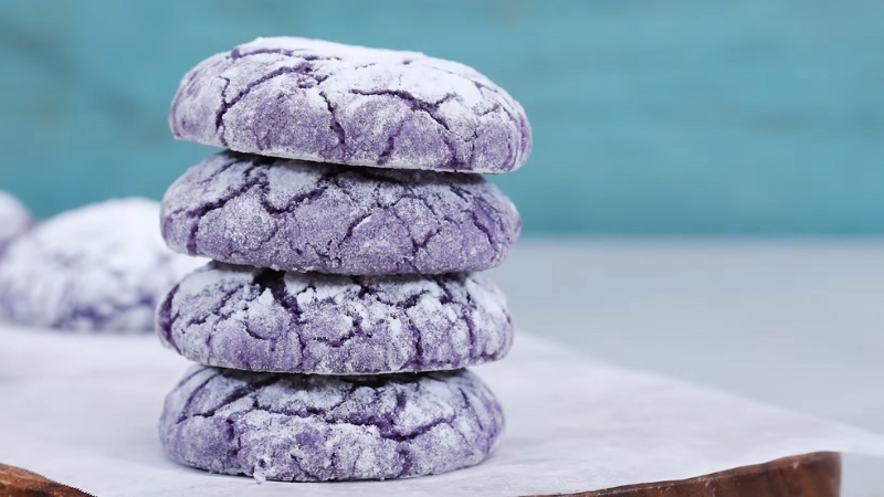 A Stack of Four Vibrant Purple Ube Crinkle Cookies Dusted with Powdered Sugar
