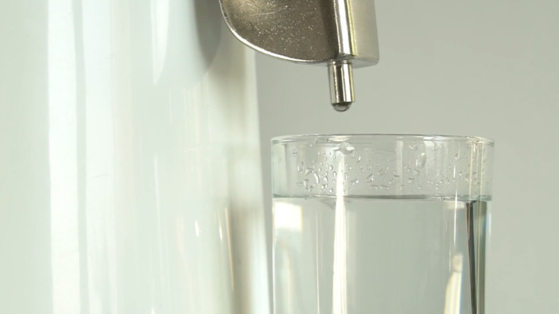 A glass being filled with purified water from a dispenser highlights how distilled and RO water impact coffee taste at home