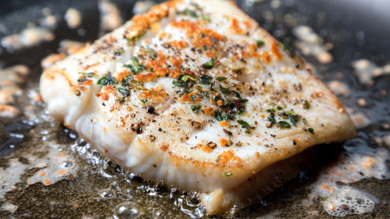 A golden seared fish fillet in a pan shows the flavor and texture gained through proper searing