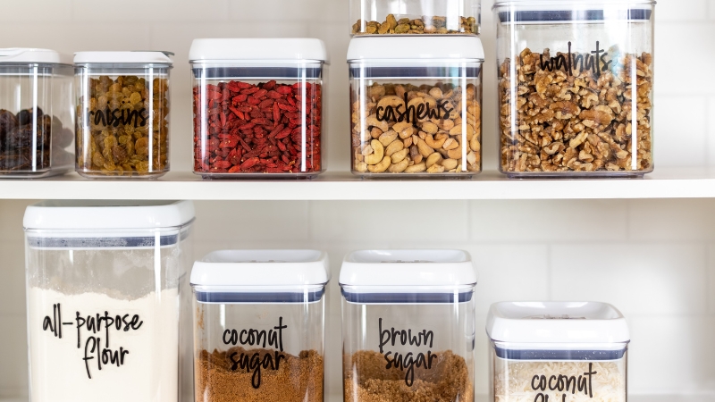 Labeled pantry with nuts, dried fruit, flour, and sugar stored in homemade jars and containers