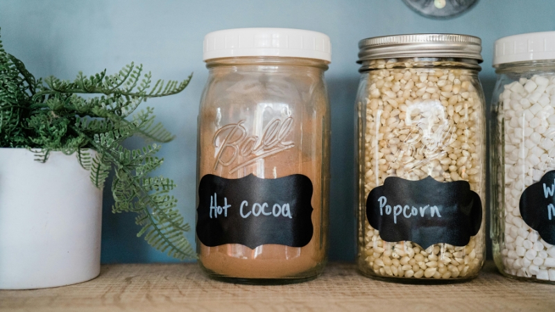 Glass jars filled with hot cocoa, popcorn, and marshmallows feature custom printed labels