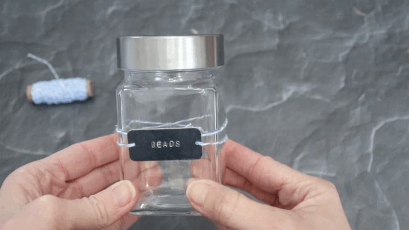 A clear jar with a metal lid features an embossed black label