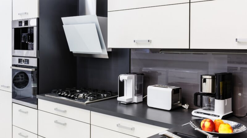 Modern white kitchen with built-in ovens and small appliances on a black counter