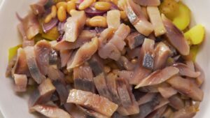 Pickled herring, potatoes, red onion, and beans combined in a mixing bowl