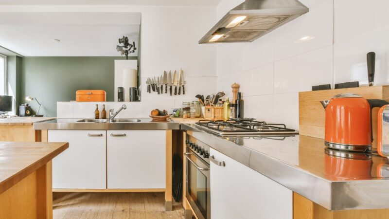 Kitchen counter with a gas cooktop, sink, knives, and orange kettle