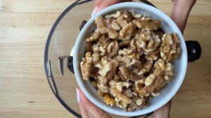 A bowl of walnuts being added to a food processor for energy balls